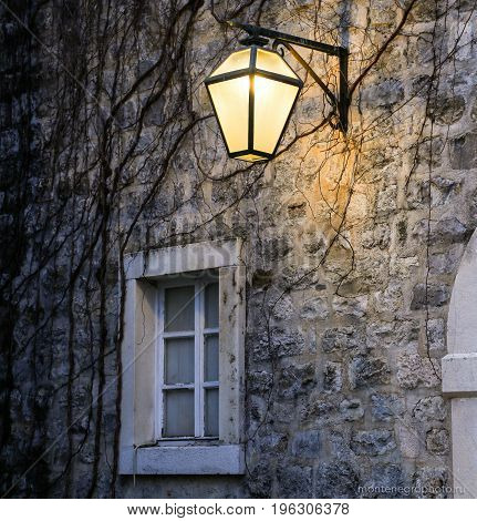 The wall of the house with a window and a lantern in the old city in European country