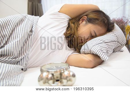 Young asian woman lying in bed watching the clock, Young woman don't want to wake up, Young woman is so broken hearted to get out of bed
