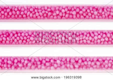 Drinking straws on white background with copy space. Top view of pink eco-friendly straws wiht strawberry balls for summer cocktails.