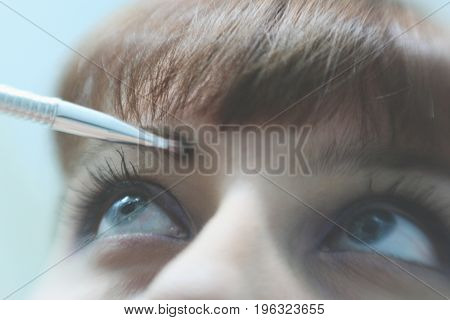 Make Up Vanity 5: self portrait of a woman applying make up to her eyebrow, shallow depth of field bring attention to her brow and bangs