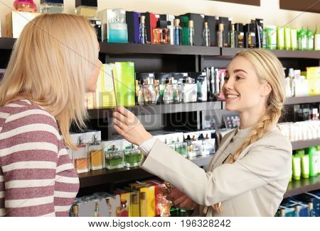 Young woman and assistant choosing perfume at store