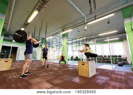 fitness, sport and exercising concept - group of people training with different equipment in gym
