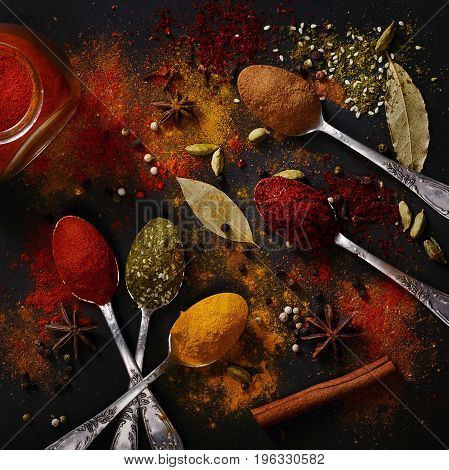 Spices on spoons on a black background shot from above