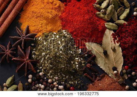 Spices scattered on a black background shot from above
