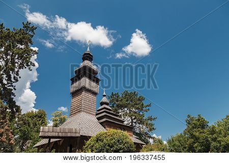 Old wooden Lemk church against a bright blue sky with clouds. Culture of Ukraine