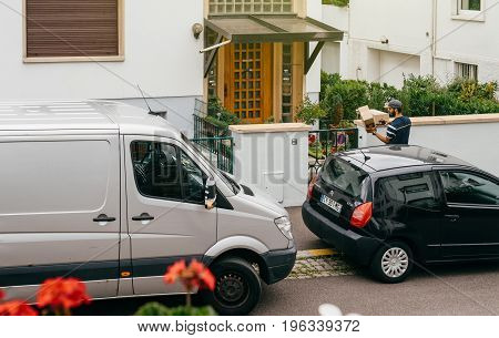 PARIS FRANCE - JUL 12 2017: Aerial view of delivery man with cardboard parcel box writing info notice to absent client to come back later to the the consignee to deliver the cardboard parcel