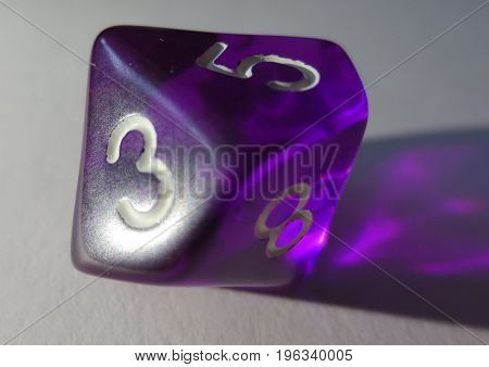purple transparent gaming dice with five up and three in front