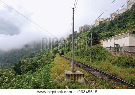 View of woods and houses around train tracks on cloudy and foggy day. Near the Lake of Albano, a quiet and bucolic countryside region near Rome. Located in the Lazio region, central Italy