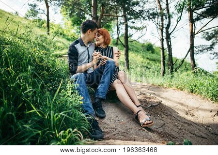 portrait of beautiful young pair in a park sitting on the ground