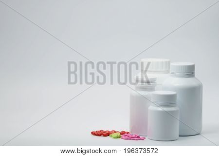 Tablet pills with closed white bottle on white background