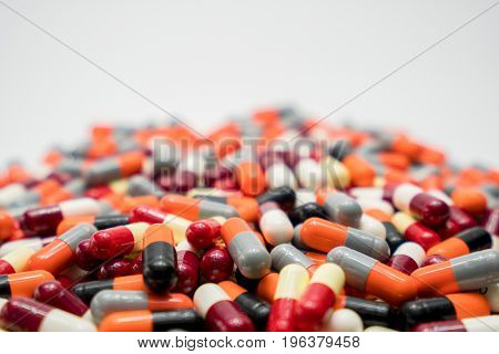 Orange black grey white red pale yellow capsule pills on white background