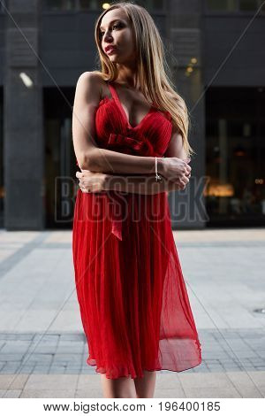 Beautiful blonde lady in red dress on White Square office center in Moscow Russia