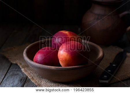 Peaches in a ceramic bowl on a wooden background