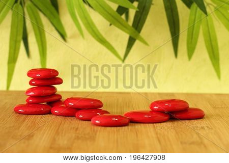 Stone red pebble laid on a wooden floor and stacked on several columns in zen lifestyle on green background