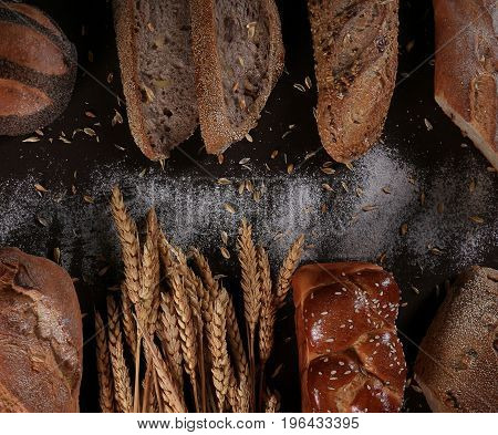 Mixed breads and rolls shot from above on a black background.