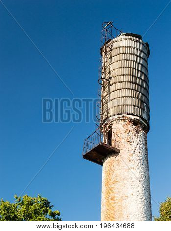 rusted industrial water tower against blue skies