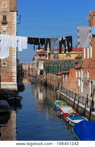 Specific canal with parked boatsspecific architecture and clothes hanging out to dry in VeniceItaly.