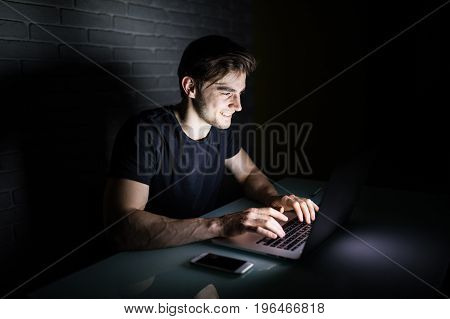 Young Man Using Laptop To Stay All Night In Social Nerworks At Home Table
