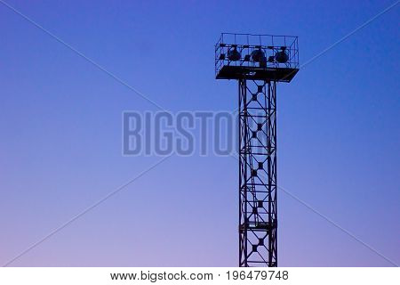 Stadium spot-light tower in a deep dawn evening