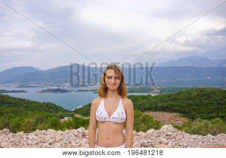 Girl teenager in a white bikini on a background of stunning nature. Fjords of Montenegro