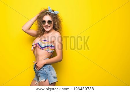 Young Beautiful Curly Woman With Happy Fency Mood In Sunglasses On Yellow Background