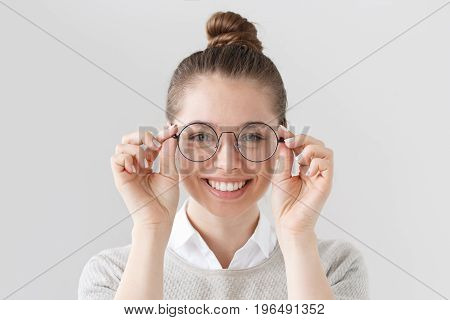Closeup Of Attractive Young Woman Isolated On Gray Background, Wearing Big Round Spectacles With Thi