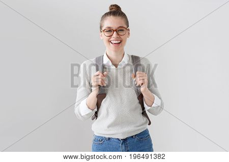 Portrait Of Energetic Teenager Girl Isolated On Gray Background Pulling Forward Straps Of Gray Hipst