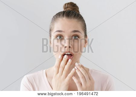 Horizontal Headshot Of Frightened Young Woman With Hair Tied In Bun Isolated On Grey Background With