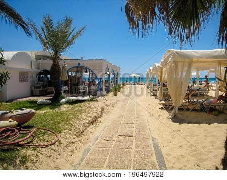 Sandy path to the hotel beach in Tunisia, clear sky