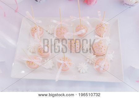 Pink cupcakes with the golden drops and ribbons on the white plate