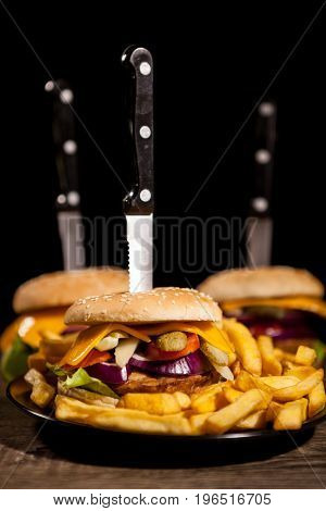 Tasty gourmet delicous burgers on black plate next to fries. Fast food. Unhealthy snack