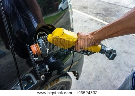Asia man's hand holding nozzle & pumping gasoline fuel in car for refuelling gas at petrol station.
