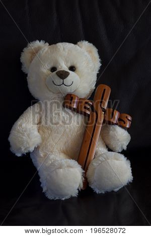 White teddy bear carrying a brown Jesus cross