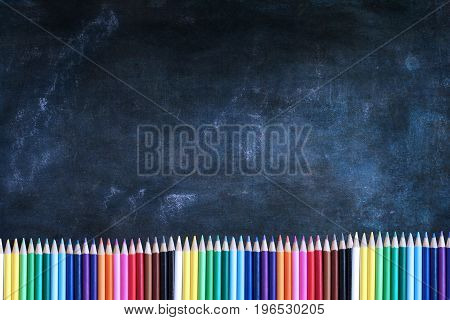 Dusty blank school chalkboard or blackboard and colored pencils with room for copy space.