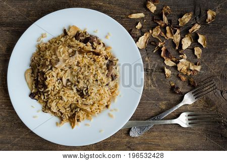 Homemade traditional Italian mushroom risotto on wooden table. Classic Risotto with mushrooms and vegetables served on a white plate. Wild mushrooms risotto. Top view.