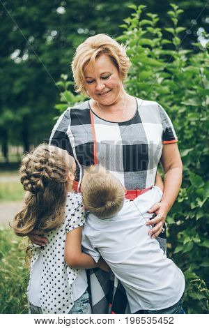 Grandmother playing in the park with grandchildren, siter with brother