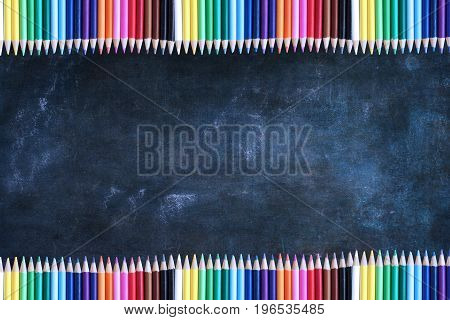 Dusty blank school chalkboard or blackboard and colored pencils with room for copy space.