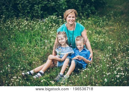 Grandmother playing in the park with grandchildren, siter with brother