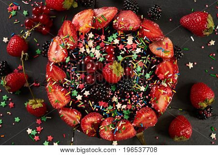 Close-up of Birthday cream cake with strawberries blueberries and blackberry on black background. Top view. Picture for a menu or a confectionery catalog.