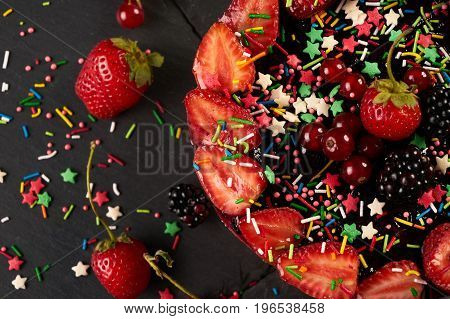 Fresh fruit and berry tart dessert dark stone background. Delicious sweet cake with raspberries strawberries blackcherry and cream. Top view