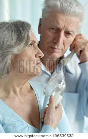 senior man taking care of ill senior woman and calling ambulance