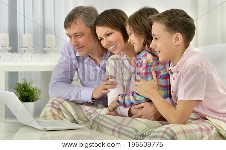 Big happy family sitting on couch an looking at laptop