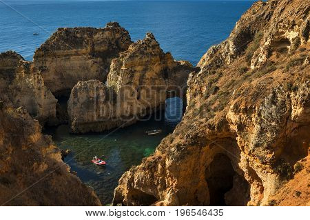 Ponta da Piedade Portugal - July 6 2017: Boats in the small bay between the sandstone cliffs at the Ponta da Piedade in Lagos Portugal