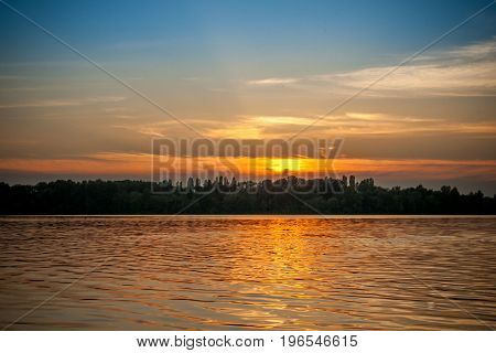 beautiful majestic sunset on the background of the river bank with some unrecognizable swimming people in Kiev Ukraine
