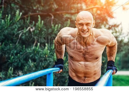 Man doing push ups on parallel bars in a park