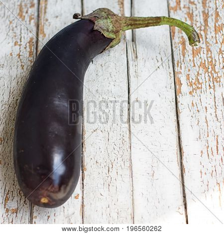 Raw eggplant with water drops on wooden table