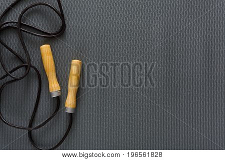 Top view of jump rope on black background. Skipping rope, fitness supply, weightloss, slimming concept