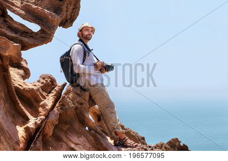 Pleased nature photographer is sitting on the edge of cliff Hormuz Island Hormozgan Province southern Iran.