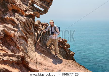 A mature traveler photographer climbs on rocks over the sea Hormuz Island Hormozgan Province Southern Iran.