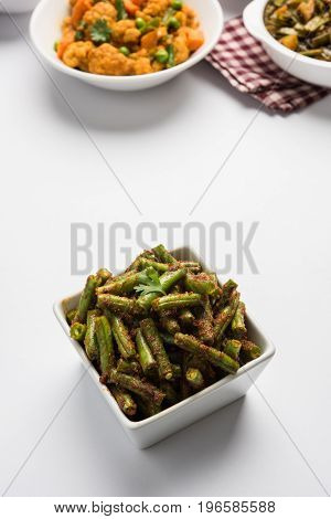 A Masala or fried vegetable dish consisting of green beans, onions, and curry spices, served in square bowl, selective focus